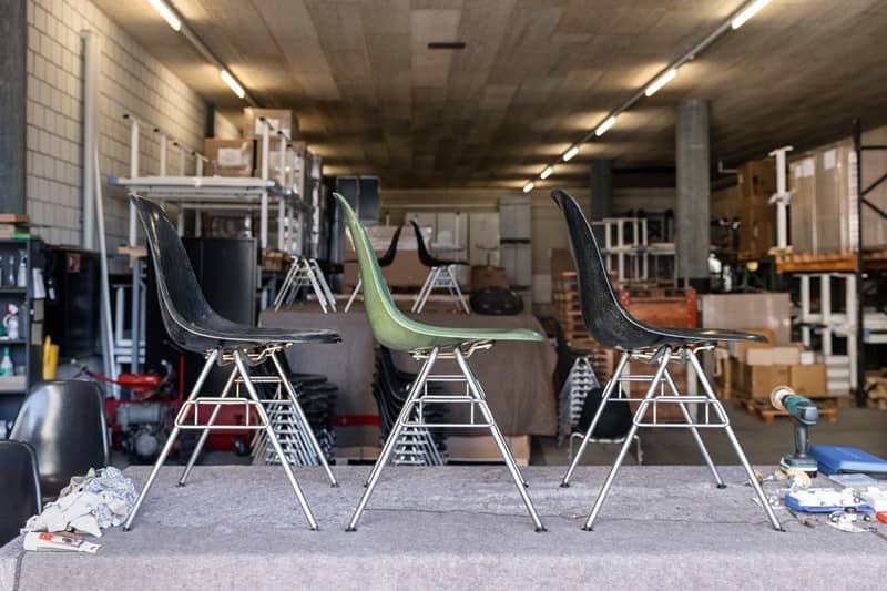 Drei gebrauchte Eames Plastic Chairs stehen in einem Lager nebeneinander